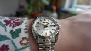 Close-up of a Seiko SNXS79 Automatic Watch on a Jubilee bracelet, showcasing the polished 5-link design and sunburst dial under soft light.